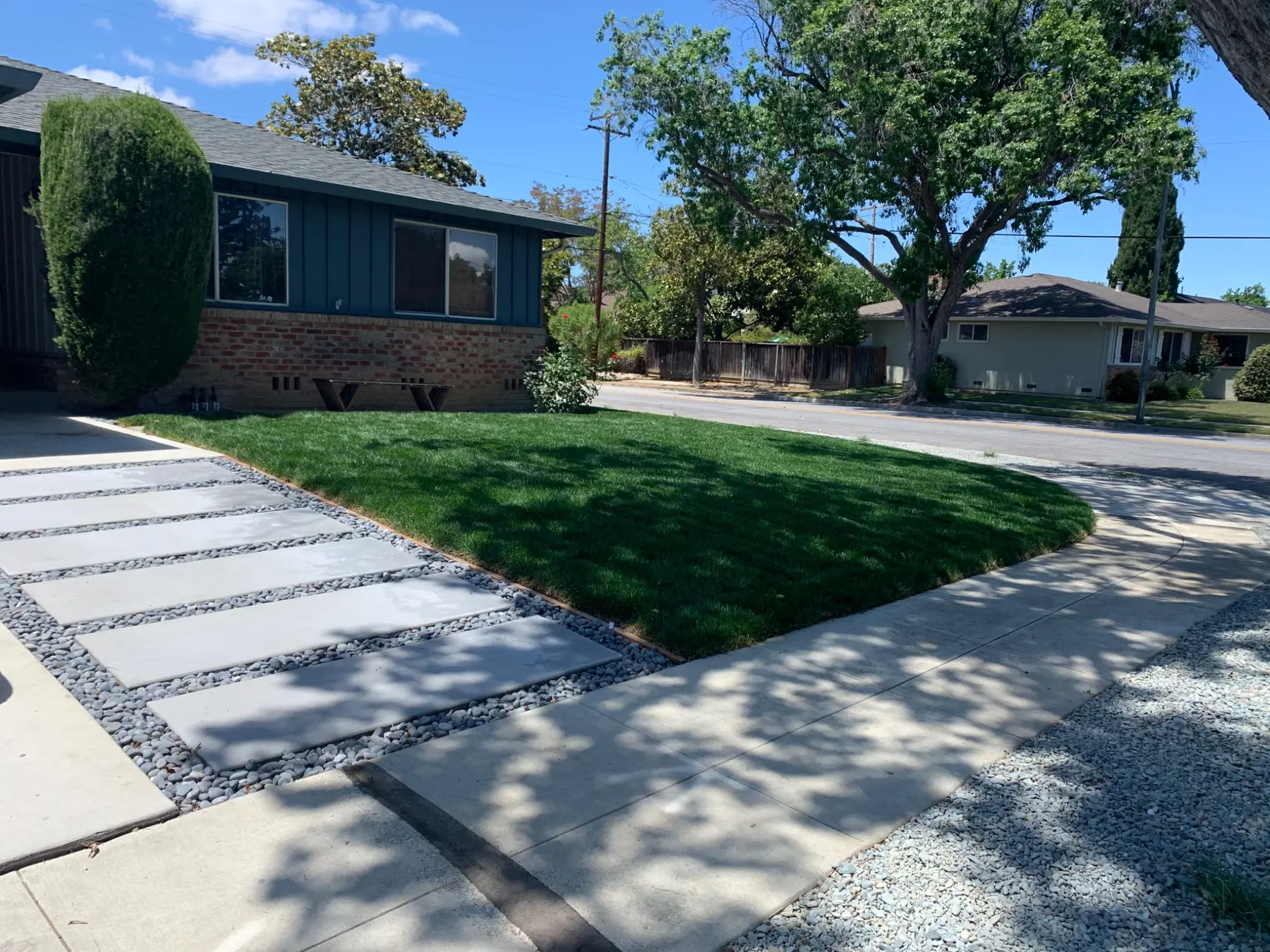 Modern front yard with turf, concrete walkway and decorative gravel completed by Garescape