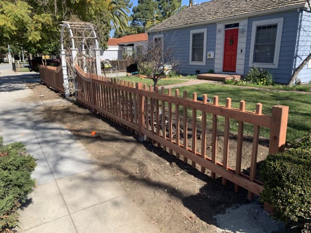 Wood fence installation surrounding a landscaped front yard